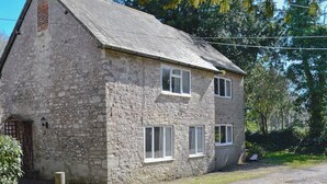 A two-story stone building with a sloped roof, multiple windows, and a visible chimney. - 3 bedroom accommodation in Winterbourne Steepleton, near Dorchester (Winterbourne Steepleton, near Dorchester)