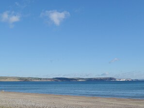A coastal landscape with a pebbly beach and a calm sea.
