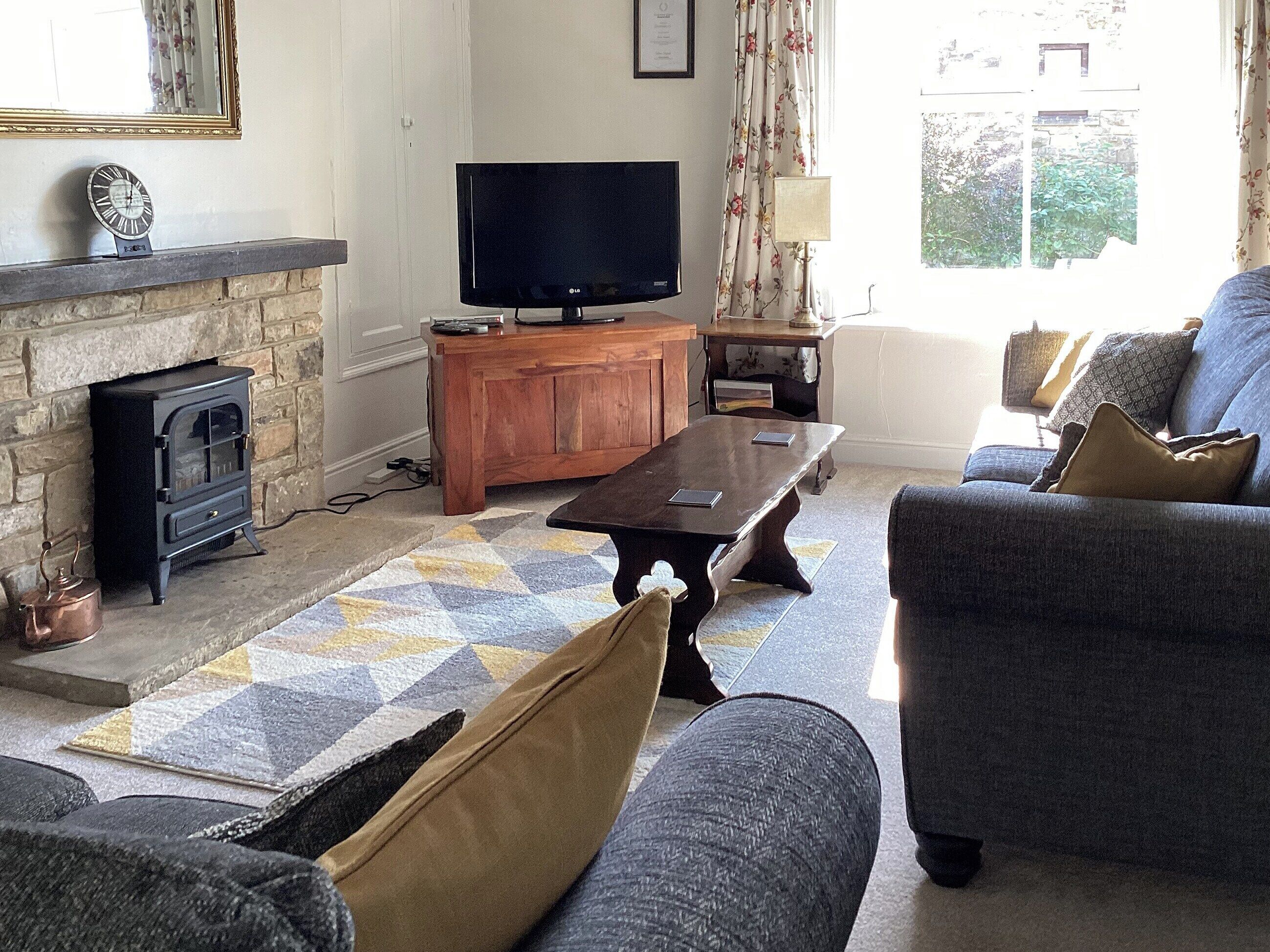 A living room with a fireplace, a television, a sofa, and a patterned rug.
