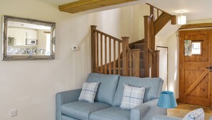 A living room with a blue sofa set, a wooden staircase, a mirror, and a door.