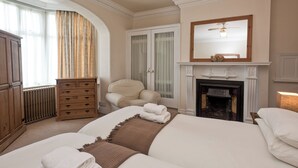 Une chambre à coucher avec un grand lit, une chaise, une cheminée et une armoire.