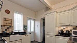 Une cuisine moderne avec des meubles blancs, un plan de travail noir, un réfrigérateur en acier inoxydable et un four à micro-ondes.