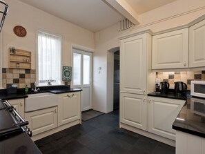 A modern kitchen with white cabinets, a black countertop, a stainless steel refrigerator, and a microwave. - 9 bedroom accommodation in Bacton (Bacton)