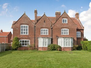 A large brick house with multiple chimneys, large windows, and a well-maintained lawn. - 9 bedroom accommodation in Bacton (Bacton)
