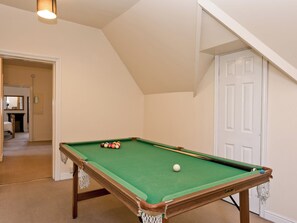 A pool table with balls in a room with a high ceiling and a door.