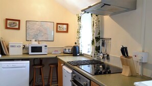 A compact kitchen with a microwave, toaster, and stove. There are stools, a dishwasher, and a sink. - Honeysuckle cottage - 23227 (Embleton, near Alnwick)