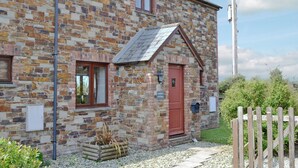 A stone cottage with a red door, a small window, and a sign indicating it is a harvest cottage. - 2 bedroom accommodation in Padstow (Padstow)