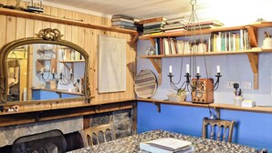 A cozy room with a stone-tiled table, wooden shelves with books, a mirror, and a fireplace. - 2 bedroom accommodation in Crovie, Gardenstown (Crovie, Gardenstown)