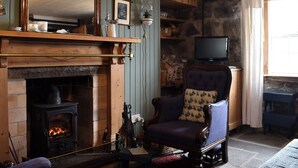 A cozy living room with a fireplace, a television, and a comfortable armchair. - 2 bedroom accommodation in Crovie, Gardenstown (Crovie, Gardenstown)