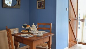 A dining table set with tea service, surrounded by wooden chairs with woven seats.
