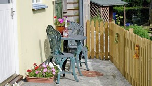 A patio with a table and chairs, a potted plant, and a wooden fence.