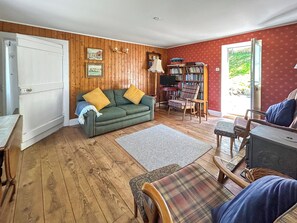A cozy living room with a sofa, armchairs, a television, and a bookshelf.