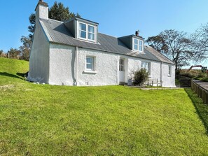 A white house with a sloped roof, a chimney, and a small porch.