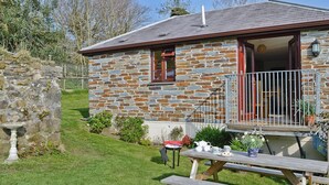 Une maison en pierre avec une terrasse en bois et une table de pique-nique.