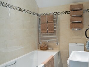 A bathroom with a bathtub, a toilet, and a towel rack with multiple towels. - 2 bedroom accommodation in Eyam, near Bakewell (Eyam, near Bakewell)