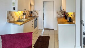 A compact kitchen with a sink, stove, and countertop appliances. - 1 bedroom accommodation in Little Tathwell, near Louth (Little Tathwell, near Louth)
