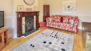 Ein Wohnzimmer mit Kamin, einer Couch, einem Teppich und einer Deckenleuchte.
