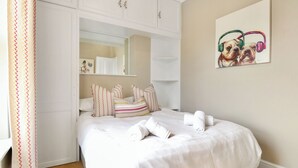 Ein Schlafzimmer mit einem Bett, Kissen, einem Spiegel und einem Bild von Hunden.
