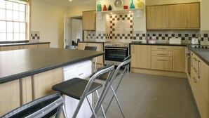 A modern kitchen with a central island, stainless steel appliances, and a checkered backsplash. - 7 bedroom accommodation in Holme-on-Spalding Moor, near Market Weighton (Holme-on-Spalding Moor, near Market Weighton)