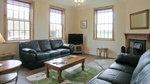A living room with a black leather sofa, a wooden coffee table, and a television on a stand. - 7 bedroom accommodation in Holme-on-Spalding Moor, near Market Weighton (Holme-on-Spalding Moor, near Market Weighton)