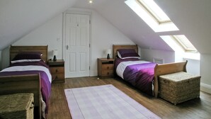 A bedroom with two beds, a skylight, a wooden floor, and a white door. - 7 bedroom accommodation in Holme-on-Spalding Moor, near Market Weighton (Holme-on-Spalding Moor, near Market Weighton)