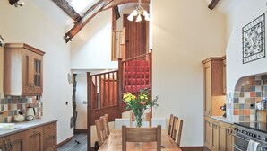 Una cocina con armarios de madera, una mesa de comedor y una escalera roja.