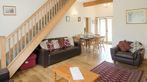 A living room with a wooden staircase, a sofa, a coffee table, and a dining area.