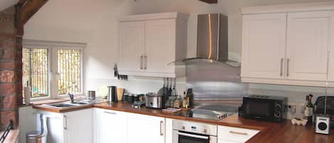 A kitchen with white cabinets, stainless steel appliances, wooden beams, and a window with bars.