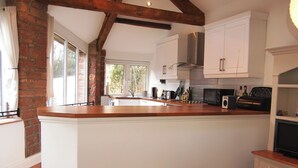 A kitchen with a wooden island, white cabinets, and a view to the outside.