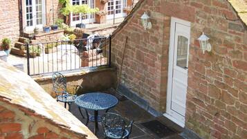 Une petite terrasse extérieure avec une table et des chaises, un mur en briques et une porte.