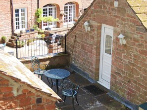 A small outdoor patio with a table and chairs, a brick wall, and a door. - A delightful courtyard setting in the beautiful Eden Valley. (near Lazonby)