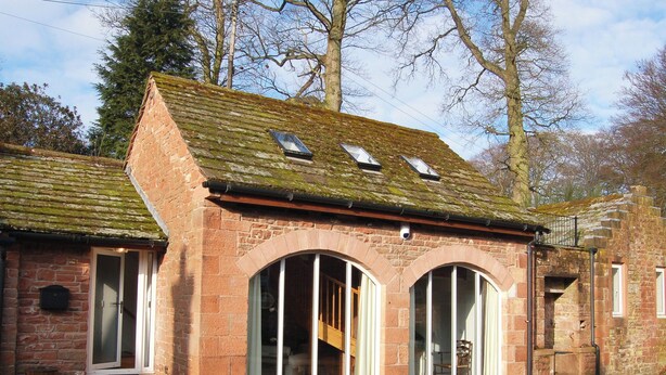 A traditional stone building with large arched windows and a sloped roof.