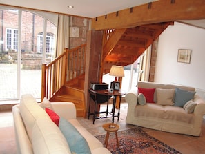 A spacious living room with a wooden staircase, a white sofa, a beige sofa, and a small table with a lamp. - A delightful courtyard setting in the beautiful Eden Valley. (near Lazonby)