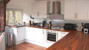 A kitchen with white cabinets, stainless steel appliances, wooden beams, and a window with bars.
