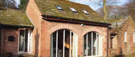 A traditional stone building with large arched windows and a sloped roof.
