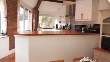 A kitchen with a wooden island, white cabinets, and a view to the outside.