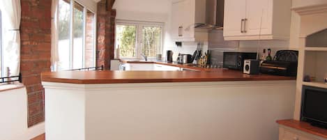 A kitchen with a wooden island, white cabinets, and a view to the outside.