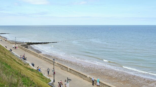 A coastal walkway with a stone wall, a sandy beach, and a calm sea. - 2 bedroom accommodation in Cromer (Cromer)