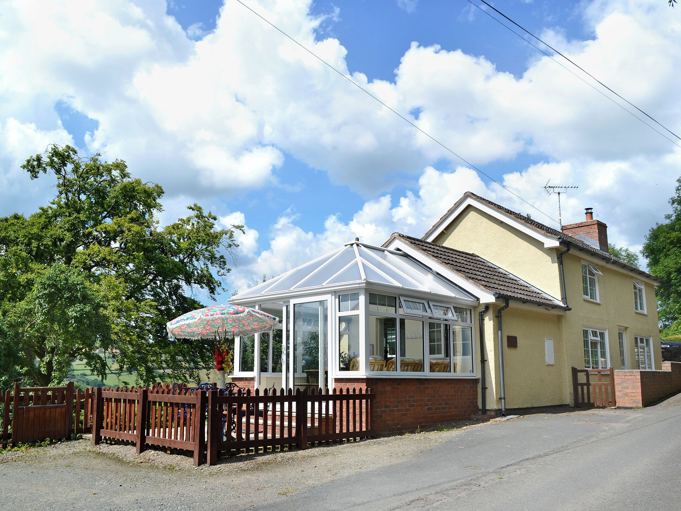 A house with a conservatory, a wooden fence, and a clear sky.
