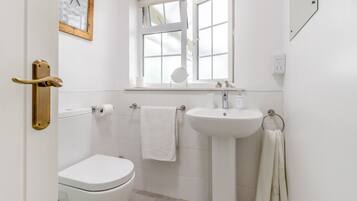 A bathroom with a toilet, sink, and window.
