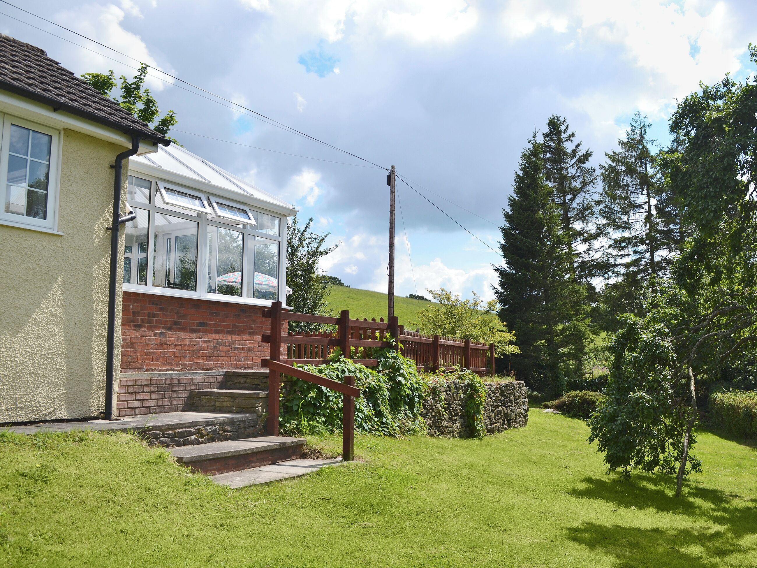 A house with a conservatory, a brick wall, and a wooden fence.