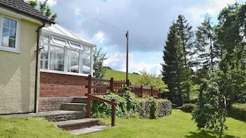 A house with a conservatory, a brick wall, and a wooden fence.