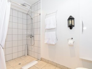 A shower with a glass door, a towel rack with two towels, a wall-mounted light fixture, and a toilet paper holder. - 1 bedroom accommodation in Thornton le Dale near Pickering (Thornton le Dale near Pickering)