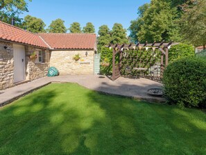 A stone building with a red-tiled roof, a pergola with climbing plants, and a well-maintained lawn. - 1 bedroom accommodation in Thornton le Dale near Pickering (Thornton le Dale near Pickering)