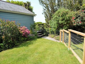 Un jardin résidentiel avec une maison, une clôture en bois et diverses plantes.