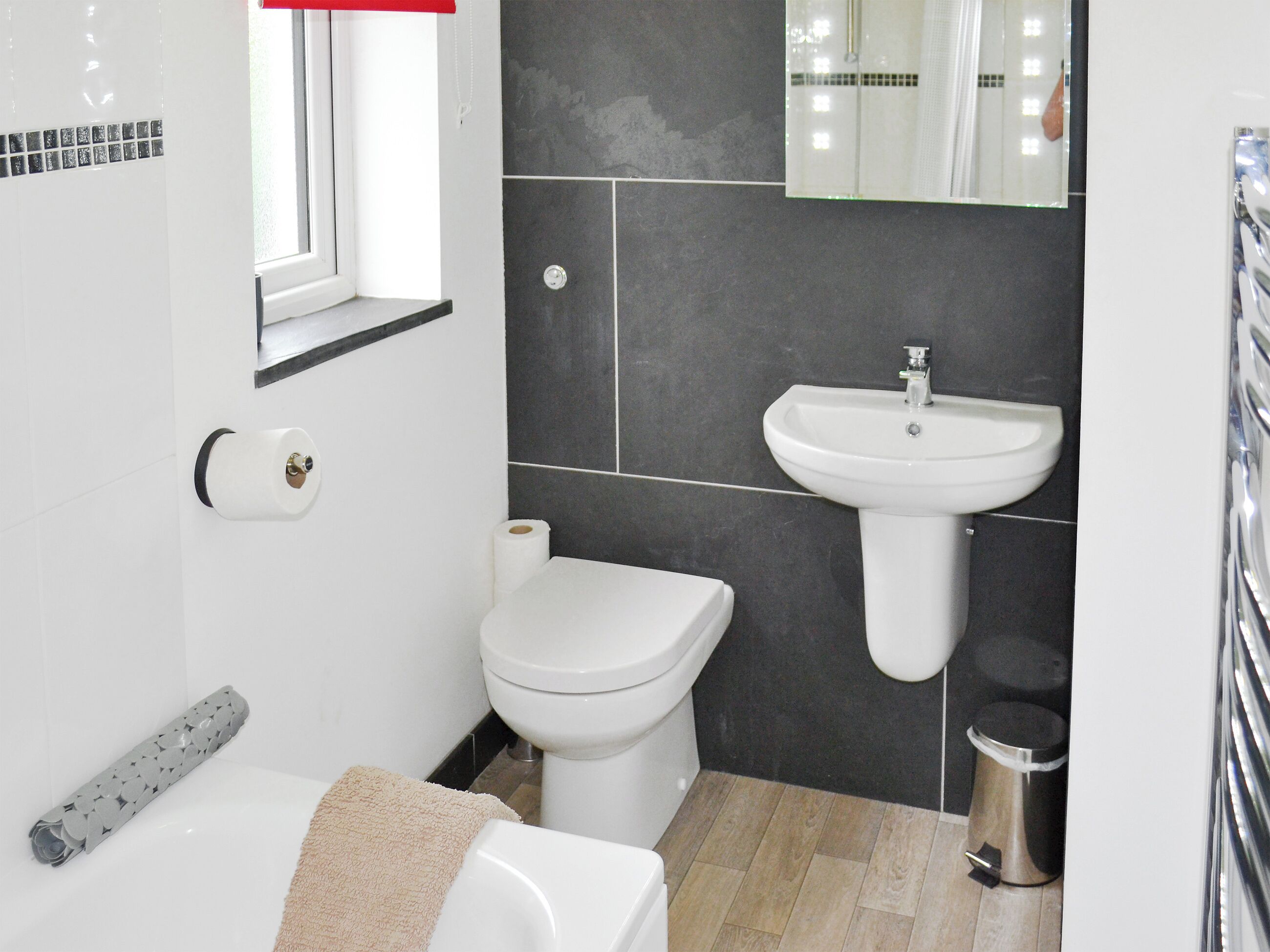 A bathroom with a toilet, sink, and mirror.