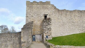 Entrada de un castillo de piedra con un camino que lleva a una puerta de madera.