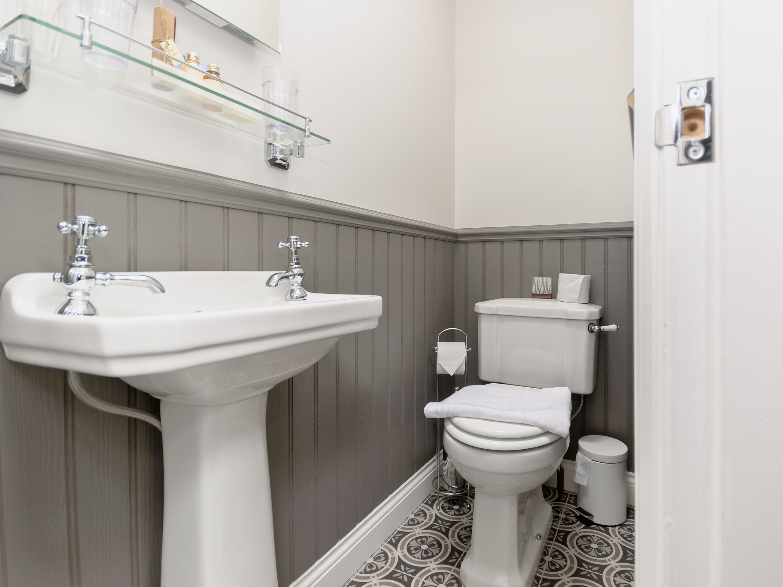 Un baño con lavamanos pedestal, inodoro y un cubo de basura.