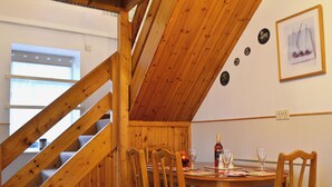 Un comedor de madera con una mesa dispuesta para cuatro, una escalera y un cuadro en la pared.