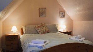 Un dormitorio con una cama, dos lámparas de noche, una mesita de noche y dos cuadros en la pared.